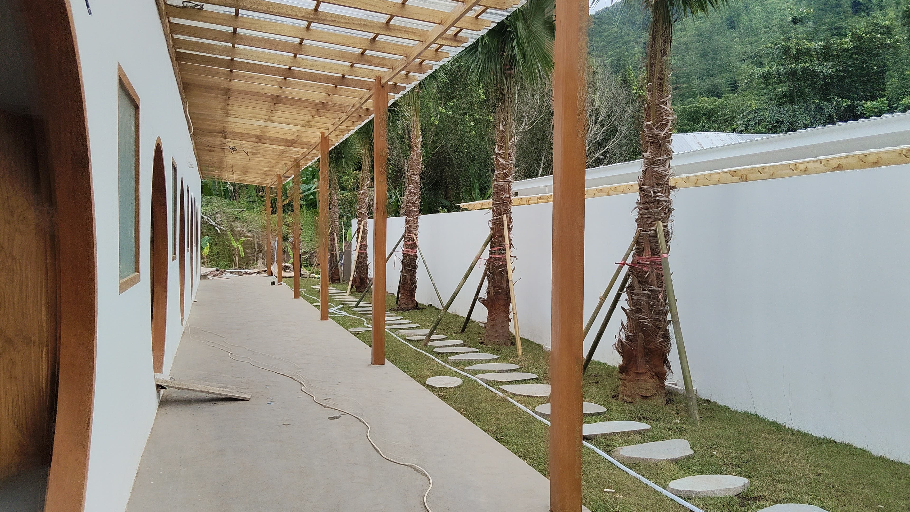 Wooden pergola with palm columns and terraced landscape