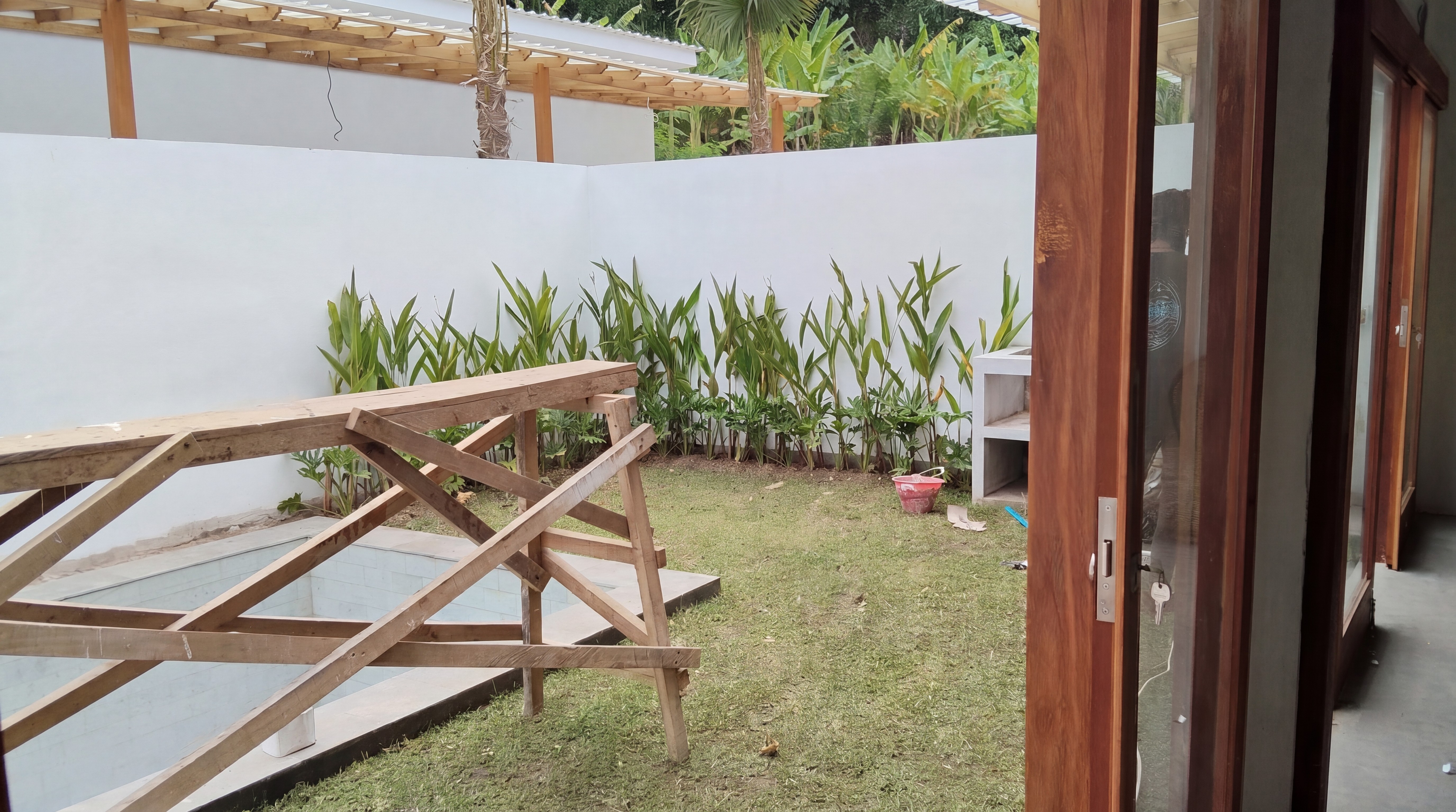 Wooden pergola framing white facade under construction