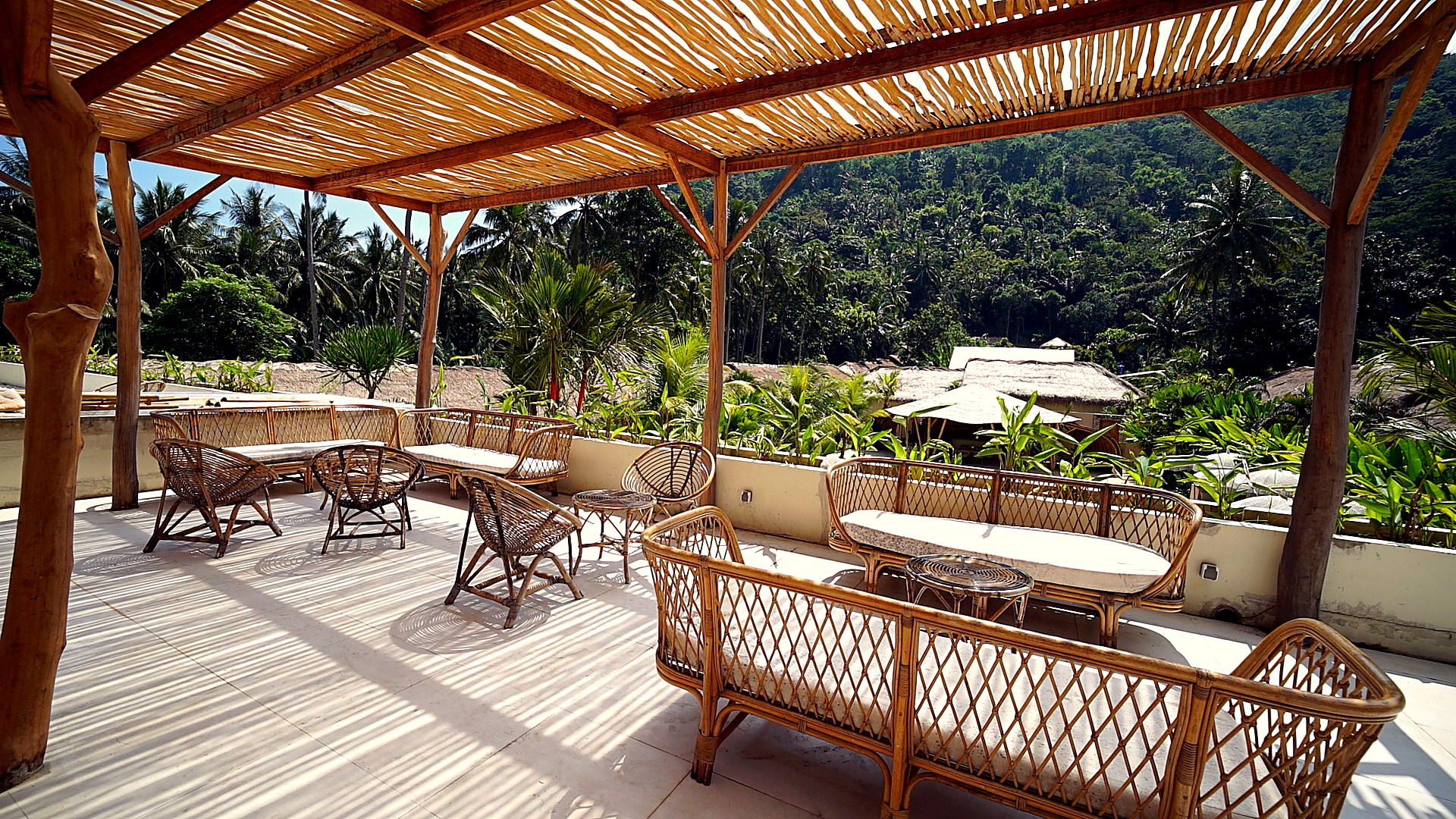 Bamboo pergola terrace with rattan lounge furniture overlooking the jungle