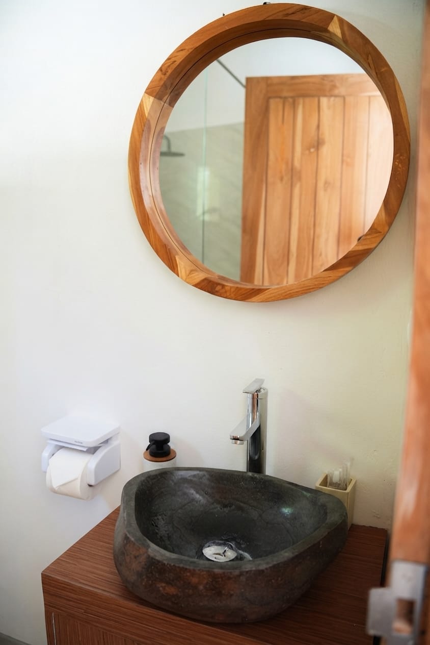 Bathroom with natural river-stone sink and teak mirror