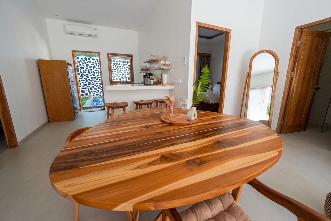 Solid teak dining table with open kitchen behind