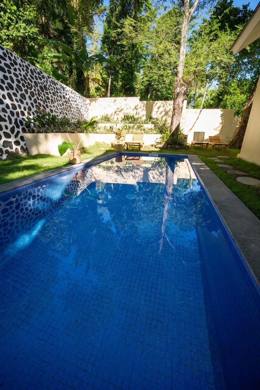 Private tiled pool framed by stone-accent walls and tropical garden