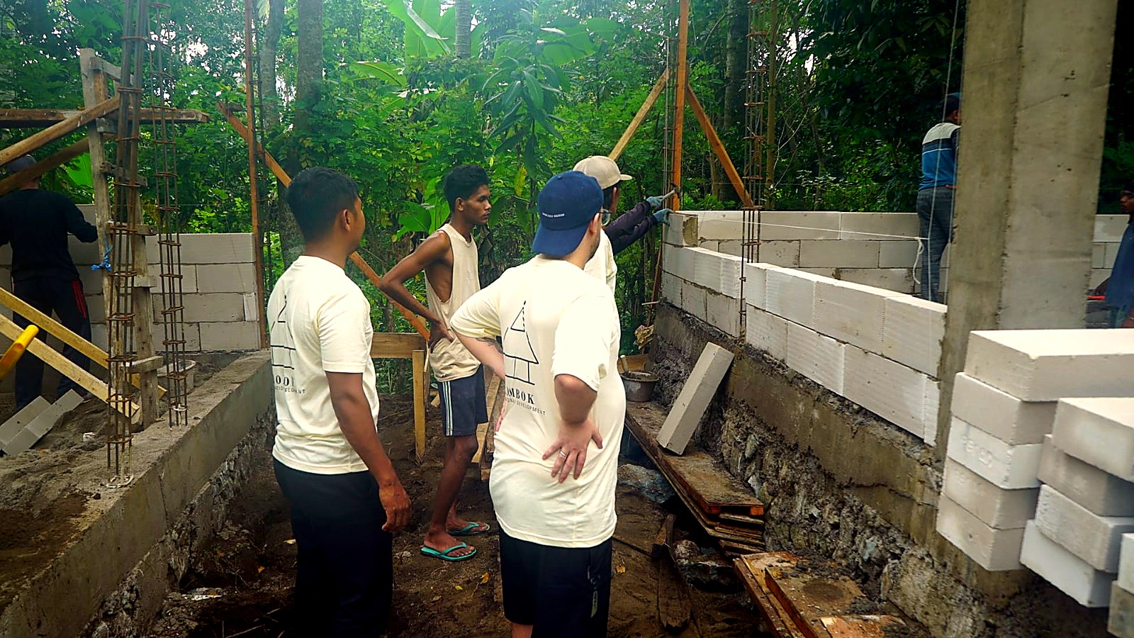 Four crew members lifting a lightweight block wall on site