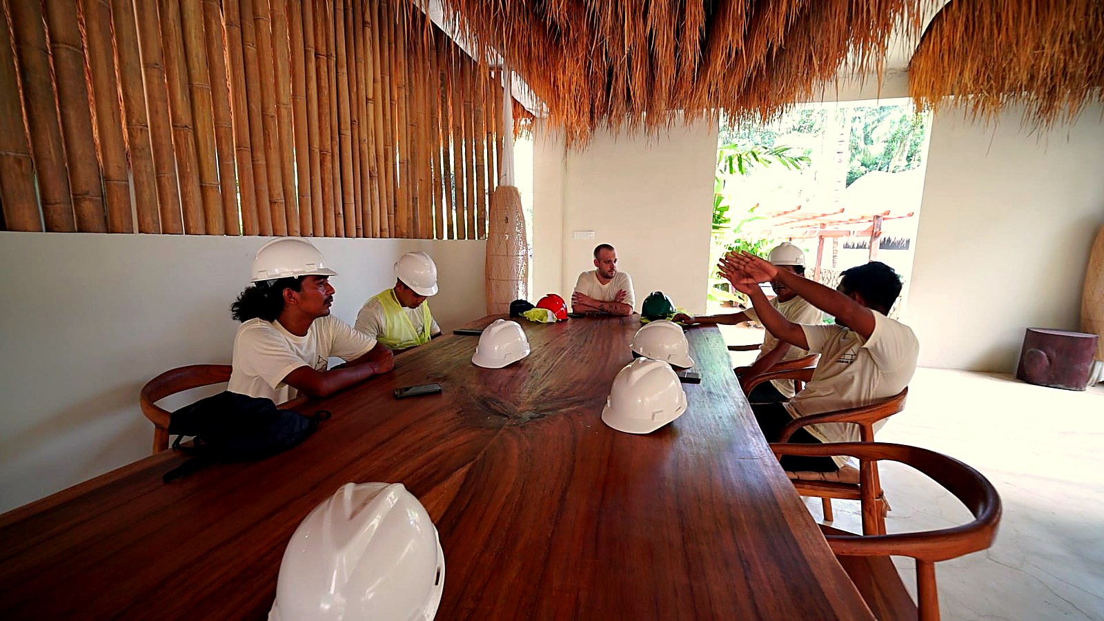 Wide view of the crew and management meeting under the thatched roof